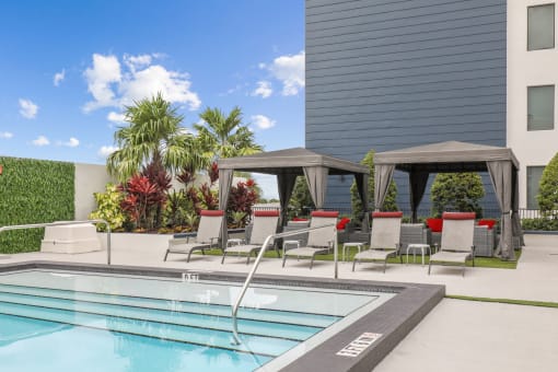 a swimming pool with lounge chairs next to a building