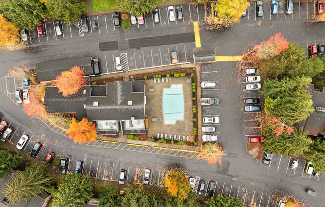 An aerial view of a parking lot with cars and a building.