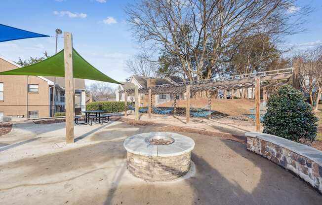 A playground with a green shade sail and a sand pit.