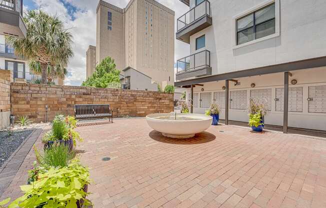 Courtyard plaza with decorative fountain and brick pavers at Vue Live Oak Apartments, Dallas