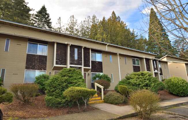 an exterior view of a tan apartment building with trees in the background