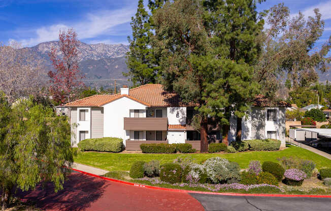 A house with a red roof is surrounded by greenery and trees.