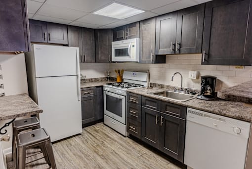 an updated kitchen with white appliances and dark cabinets