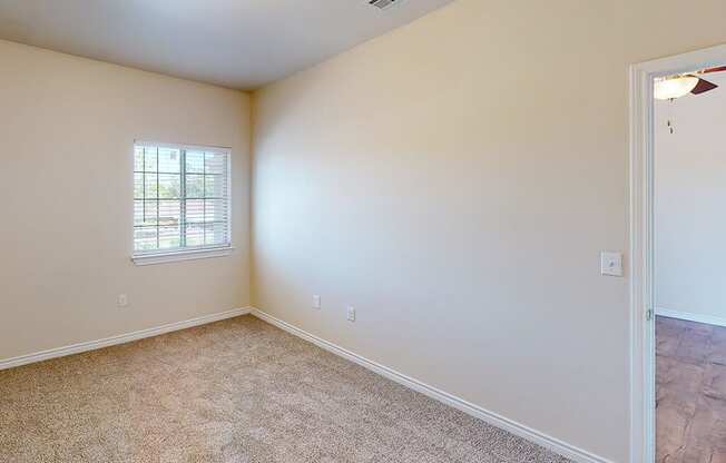 an empty living room with a window and carpet