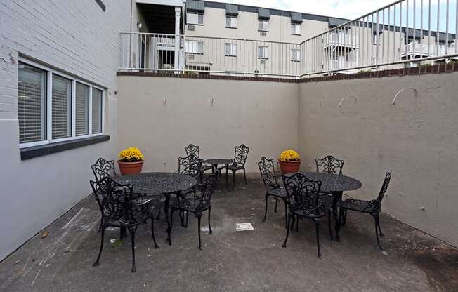 an outdoor patio with tables and chairs and a building in the background