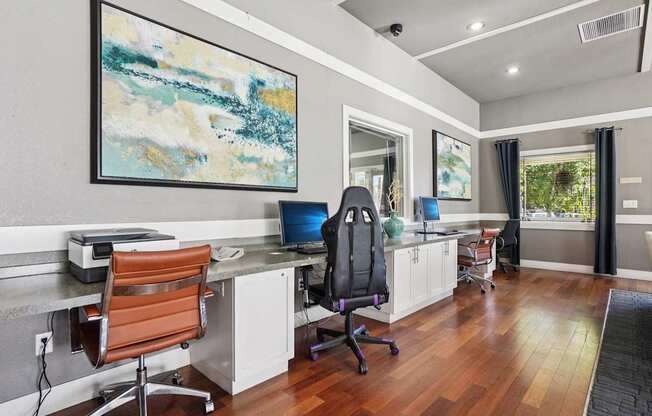 A modern home office with a wooden floor and a large abstract painting on the wall.