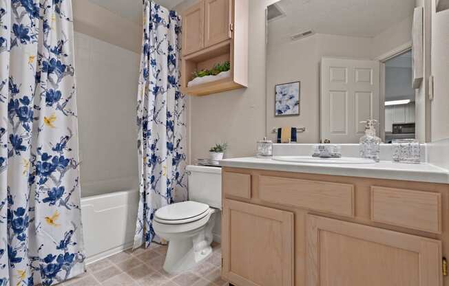 a bathroom with a white toilet next to a bathtub with a blue and white shower curtain