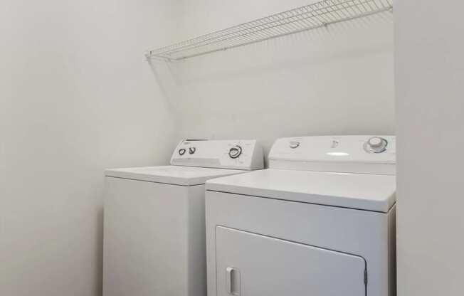 Two white washing machines in a laundry room.