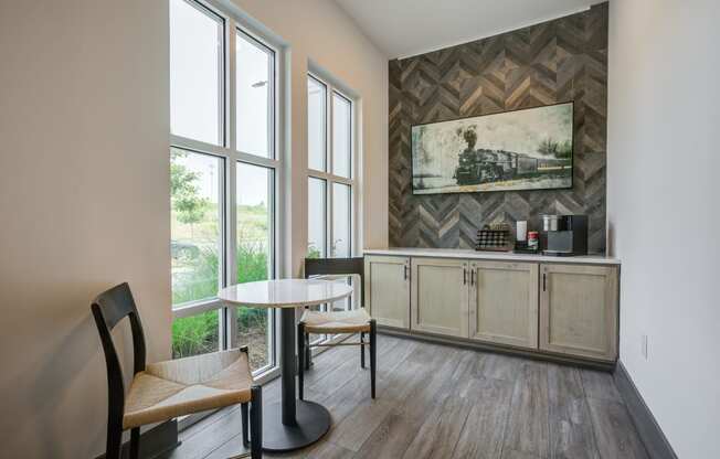 a seating area with a table and two chairs in front of a large window with a coffee at Century University City, North Carolina, 28213