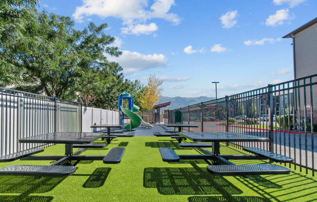 a picnic area with picnic tables and a slide on a sunny day