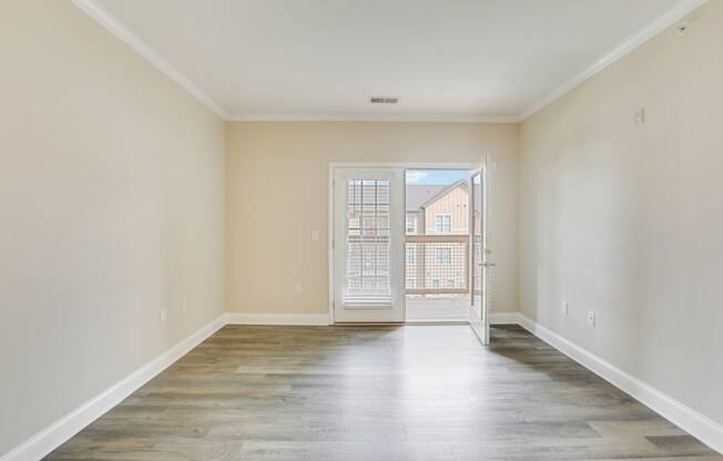 an empty living room with a door to a balcony