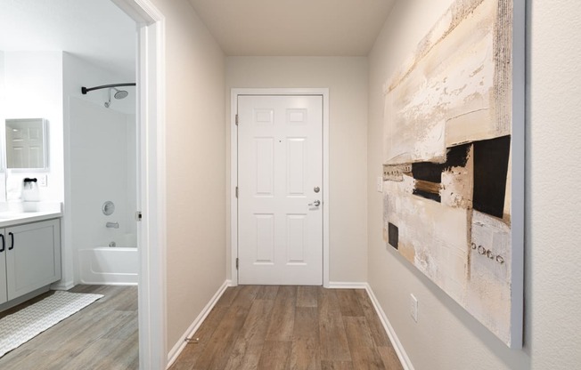 a hallway with a white door and a large painting on the wall