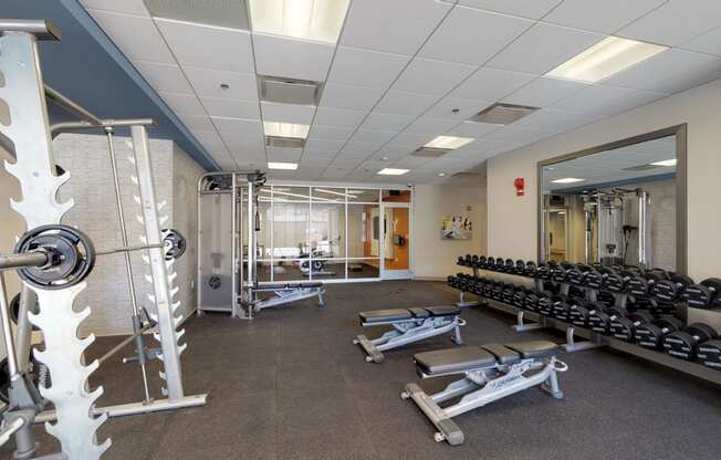 a large fitness room with free weights and mirrors