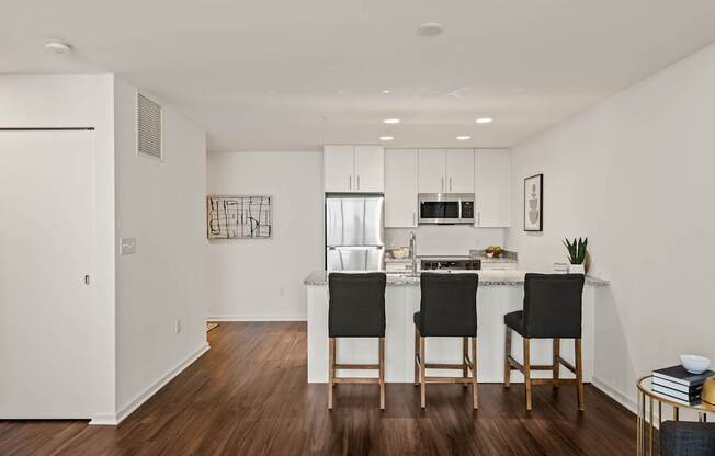 A kitchen with a white countertop and black chairs.