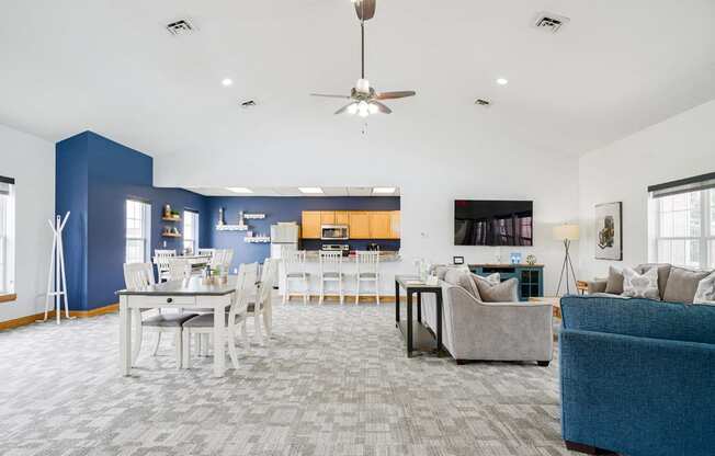 Community clubhouse with couches and a dining room with a table and chairs with the kitchen in the back