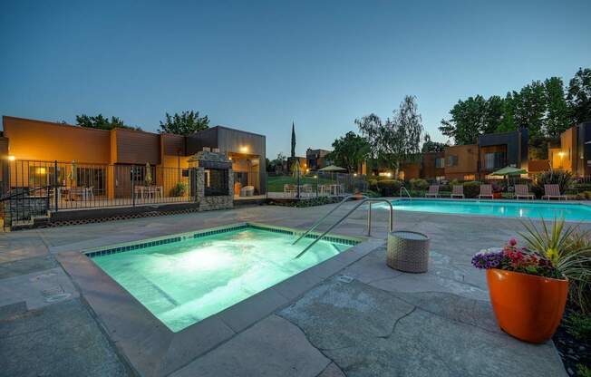 A swimming pool surrounded by a stone patio and a building in the background.