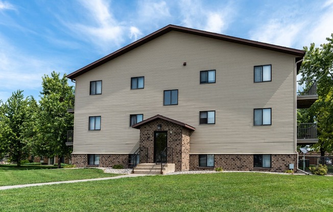 An apartment building with a grassy yard in front of it. Fargo, ND Granger Court Apartments.