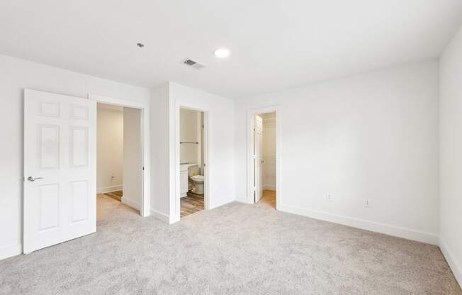 A bed room with a carpeted floor and a door on the left.