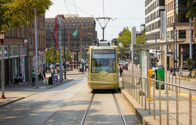 a yellow tram traveling down a street next to tall buildings