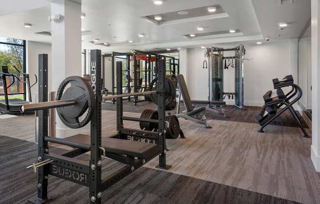 A gym with a variety of equipment including a squat rack, bench press, and a rowing machine.
