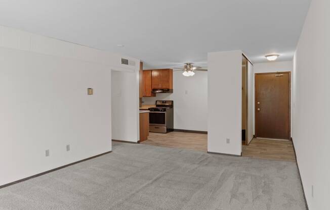 a bedroom with a ceiling fan and a kitchen in the background