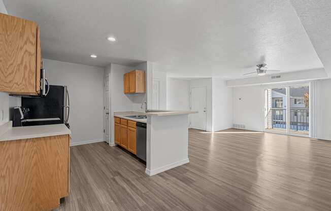 View of expansive living room and kitchen area with plank flooring, natural light, and a sliding glass dooes that lead to a patio or balcony at Eagles Landing, Idaho, 83406