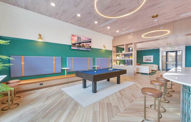 A room with a pool table and bar stools.