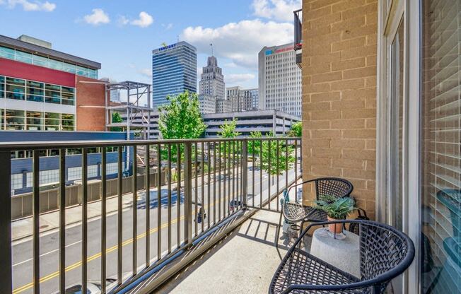 the view of the city from the balcony of a condo with a chair and table at Link Apartments Innovation Quarter, Winston Salem, NC, 27101