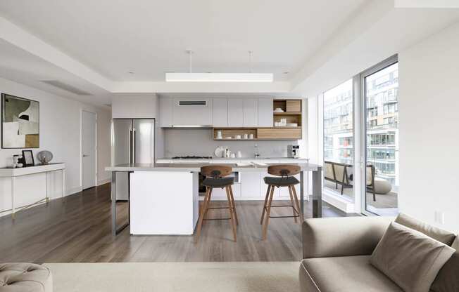 a kitchen with white cabinetry and a white island with three wooden stools