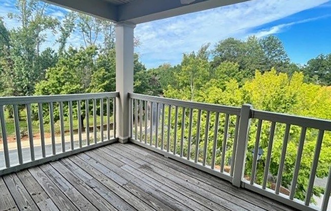 a porch with a ceiling fan and a view of trees