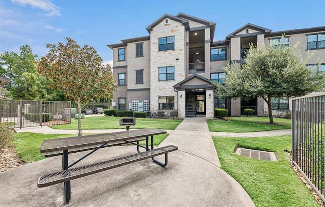A large apartment complex with a picnic table in front.