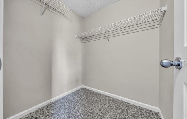 an empty closet with an open door and a shelf on the wall