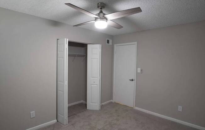 A room with a ceiling fan and two doors.