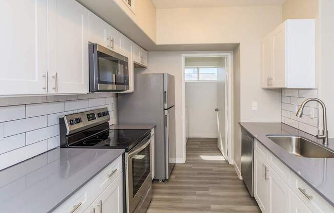 A kitchen with white cabinets and a black counter top.