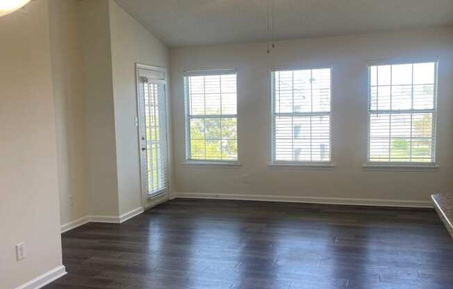 an empty living room with wood floors and a ceiling fan