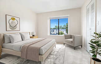 A bedroom with a large bed and a chair by the window at Emerald Park Apartments, Kalamazoo, Michigan