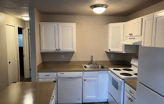 a kitchen with white cabinets and white appliances and counter tops