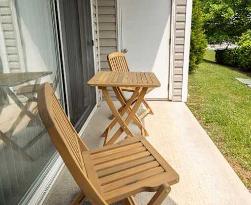 A wooden chair and table are on a patio.