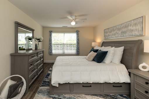 A bedroom with a large bed, a dresser, and a ceiling fan.