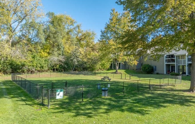 A sunny day at a park with a picnic table and a fence.