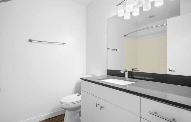 A white bathroom with a toilet, sink, and mirror.