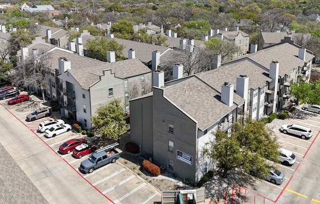 An aerial view of an apartment complex with parking and a dumpster at The Park on Preston Apartments in Dallas, TX