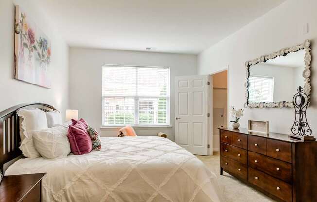 A bedroom with a large bed, a dresser, and a mirror.