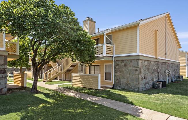 Exterior of Windrush Apartment Homes with large shade tree and well-kept lawn