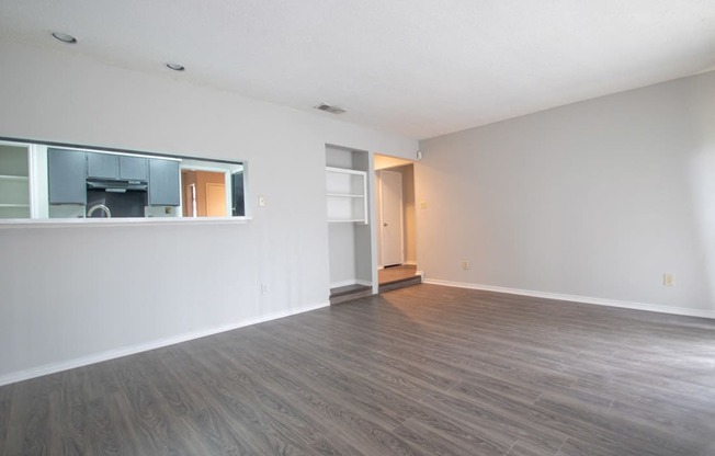 an empty living room with a wood floor and white walls at The Broadwater at Salado Creek, San Antonio, Texas