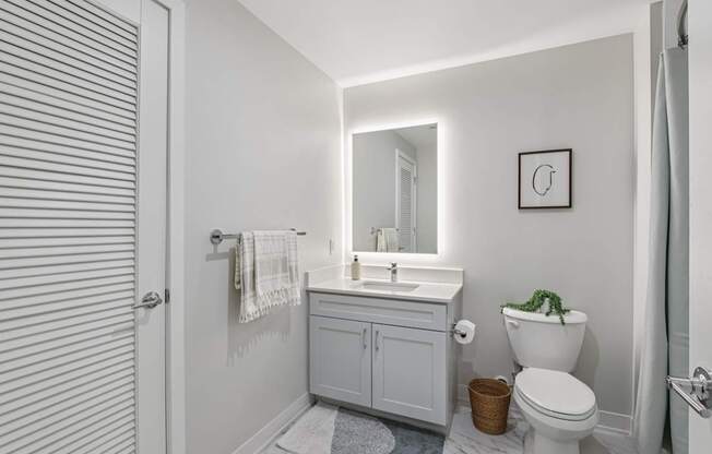 A white bathroom with a toilet, sink, and mirror.