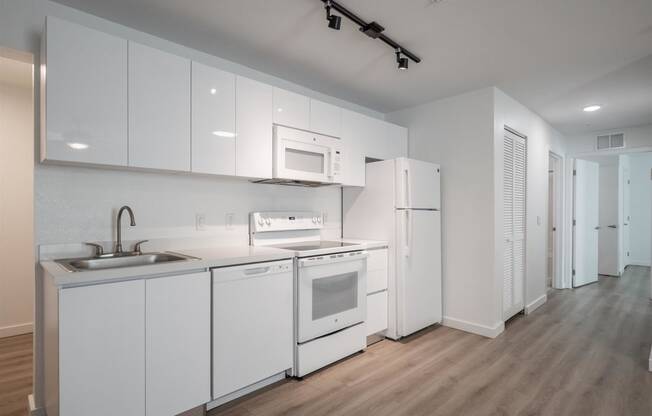 a kitchen with white cabinets and appliances and a sink and a refrigerator