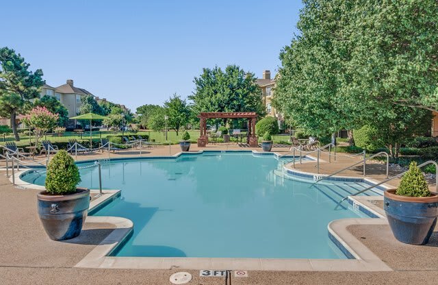 a swimming pool with trees and a gazebo in the background
