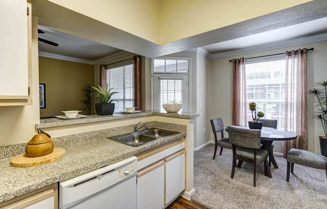 A kitchen with a table and chairs in front of a window.