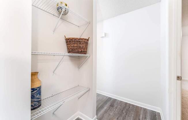 a walk in closet with shelves and a basket on the wall
